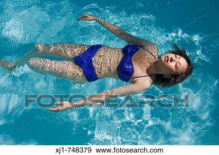 Stock Photo - A young Japanese woman swimming in a pool.. Fotosearch