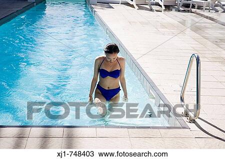Stock Image - A young Japanese woman walks toward the end of the pool, about to step out.. Fotosearch
