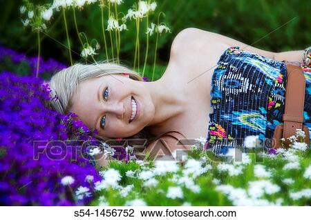 Stock Image - A young lady outdoors in a flower garden.. Fotosearch