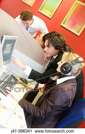 A young man and lady at work on a computer, she's wearing headphones, hes standing and pointing at the screen smiling View Large Photo Image Stock Image - A young man and lady at work on a computer, she's wearing headphones, hes standing and pointing at the screen smiling. Fotosearch