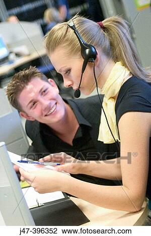 A young man and lady in suits, sitting at a computer, looking at papers, shes wearing a headset View Large Photo Image Stock Image - A young man and lady in suits, sitting at a computer, looking at papers, shes wearing a headset. Fotosearch
