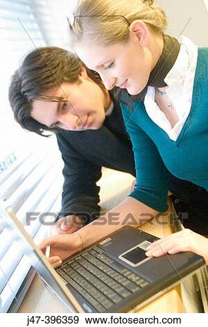 A young man and lady leaning on a windowsill woking on a laptop, smiling View Large Photo Image Stock Photo - A young man and lady leaning on a windowsill woking on a laptop, smiling. Fotosearch