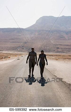 A young man and woman covered in mud walking to the Dead Sea, desert scenery behind them, Israel. View Large Photo Image Stock Image - A young man and woman covered in mud walking to the Dead Sea, desert scenery behind them, Israel.. Fotosearch