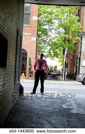 A young man in business clothes standing at the end of an alley. View Large Photo Image Stock Image - A young man in business clothes standing at the end of an alley.. Fotosearch