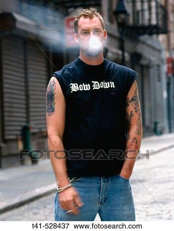 A young man smoking in the downtown streets of Manhattan. He is smoking Marlboro Reds and his tattoos are of pin-up girls. His shirt says? bow down?. View Large Photo Image Stock Photo - A young man smoking in the downtown streets of Manhattan. He is smoking Marlboro Reds and his tattoos are of pin-up girls. His shirt says? bow down?.. Fotosearch