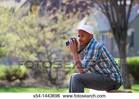 Stock Photograph - A young man taking pictures at a park.. Fotosearch