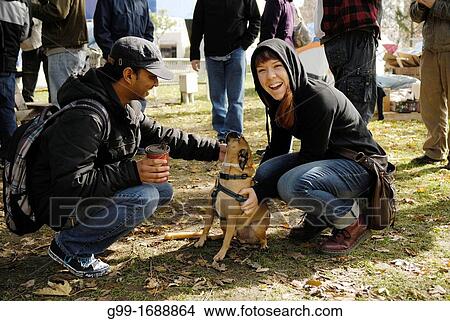 Picture - A young man watches tentatively as a young woman pets her dog at Occupy Windsor, located in Canada. Fotosearch