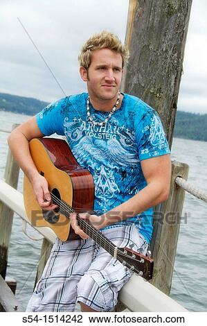 A young man with a guitar outdoors in Coeur d? Alene, Idaho, USA View Large Photo Image Stock Image - A young man with a guitar outdoors in Coeur d? Alene, Idaho, USA. Fotosearch