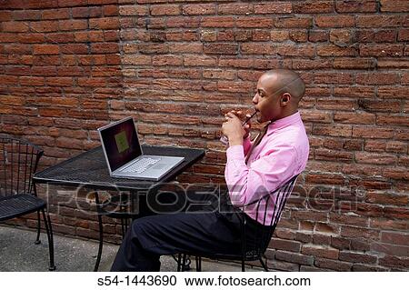 Stock Image - A young man working on a laptop outdoors.. Fotosearch