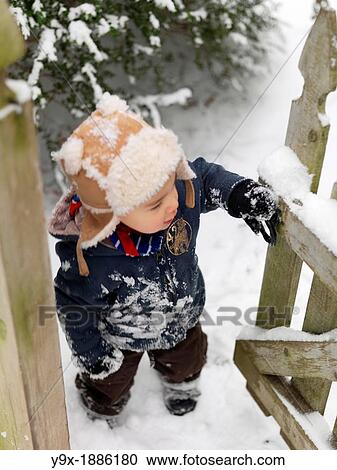 A young mixed ethnicity child playing in the snow and opening a wooden gate View Large Photo Image Stock Image - A young mixed ethnicity child playing in the snow and opening a wooden gate. Fotosearch
