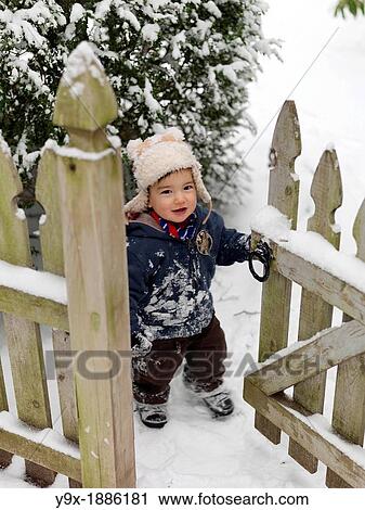 A young mixed ethnicity child playing in the snow and opening a wooden gate View Large Photo Image Stock Image - A young mixed ethnicity child playing in the snow and opening a wooden gate. Fotosearch
