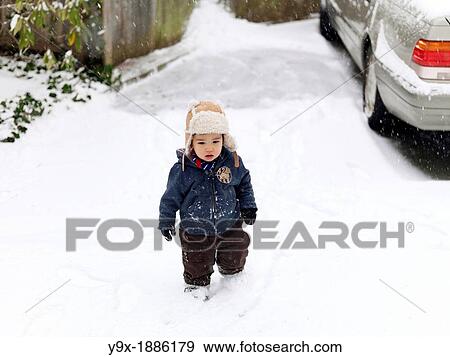 Stock Photo - A young mixed ethnicity child playing in the snow. Fotosearch