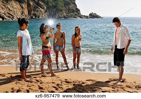 A young teenage girl photographing a model on the beach, fans girls are happy View Large Photo Image Stock Photo - A young teenage girl photographing a model on the beach, fans girls are happy. Fotosearch