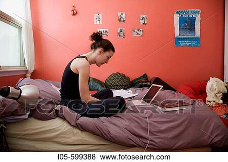 Stock Photo - A young woman 20 years old sitting in her room working on university homework. Fotosearch
