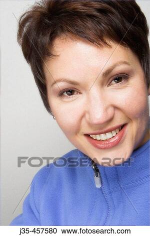Stock Image - A young woman 20's - 30's wearing a light blue fleece looks into camera with smile. Fotosearch