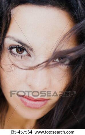 A young woman 20's to 30's with long dark hair with a calm, pensive expression looks into the camera View Large Photo Image Picture - A young woman 20's to 30's with long dark hair with a calm, pensive expression looks into the camera. Fotosearch