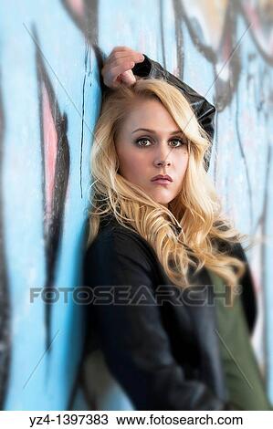 A young woman by a wall covered in graffiti View Large Photo Image Stock Image - A young woman by a wall covered in graffiti. Fotosearch