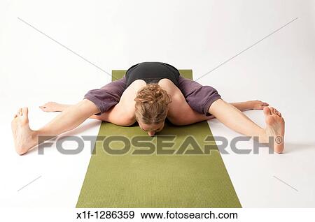 Stock Photo - A young woman doing yoga on a green mat. Fotosearch