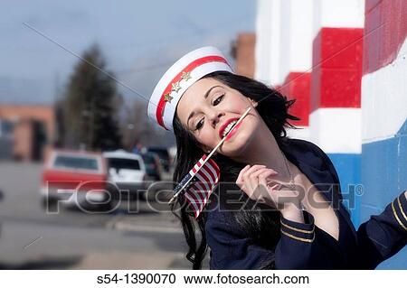 Stock Image - A young woman dressed as a sailor in a pin-up style, with an American flag. Fotosearch