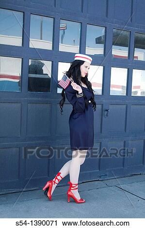 A young woman dressed as a sailor in a pin-up style, holding an American flag View Large Photo Image Stock Image - A young woman dressed as a sailor in a pin-up style, holding an American flag. Fotosearch