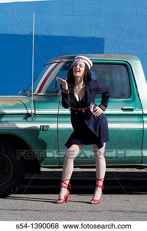 Stock Photo - A young woman dressed as a sailor in a pin-up style, holding an American flag. Fotosearch