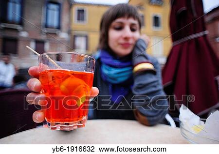 Stock Image - A young woman drinking an Aperol Spritz in Venice, Italy. Fotosearch