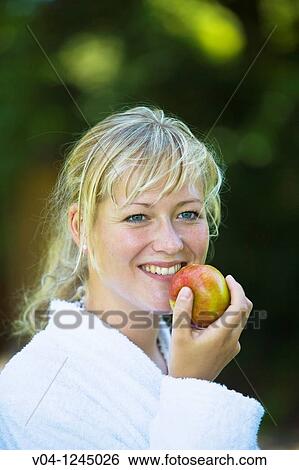 A young woman eating an apple and smiling broadly View Large Photo Image Stock Photograph - A young woman eating an apple and smiling broadly. Fotosearch