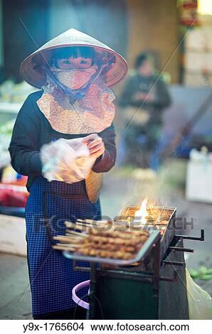 A young woman grilling chicken satay on the street View Large Photo Image Picture - A young woman grilling chicken satay on the street. Fotosearch