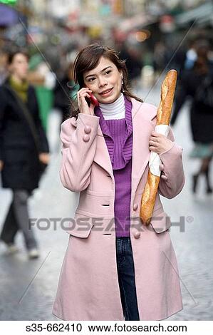A young woman holding a baguette and talking on her cell phone on the street of Paris. Paris. France. View Large Photo Image Stock Image - A young woman holding a baguette and talking on her cell phone on the street of Paris. Paris. France.. Fotosearch