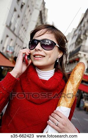 A young woman holding a baguette and talking on her cell phone on the street of Paris. Paris. France. View Large Photo Image Stock Image - A young woman holding a baguette and talking on her cell phone on the street of Paris. Paris. France.. Fotosearch
