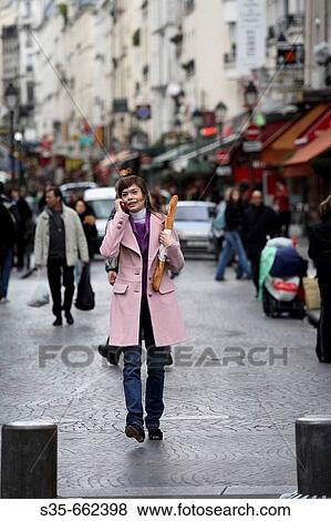 A young woman holding a baguette and talking on her cell phone on the street of Paris. Paris. France View Large Photo Image Stock Photo - A young woman holding a baguette and talking on her cell phone on the street of Paris. Paris. France. Fotosearch