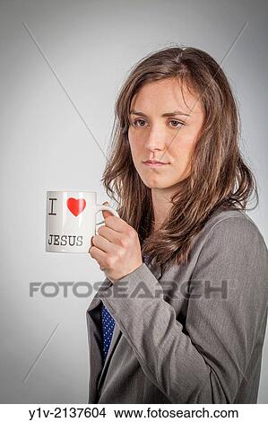 A young woman holding a mug with "I love Jesus" written on the side. View Large Photo Image Picture - A young woman holding a mug with "I love Jesus" written on the side.. Fotosearch