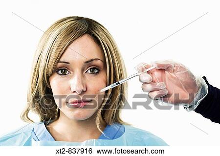 A young woman is injected with a syringe containing botox View Large Photo Image Stock Photograph - A young woman is injected with a syringe containing botox. Fotosearch