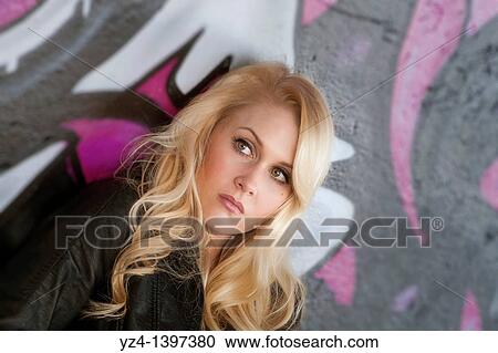 A young woman leaning against a wall covered with graffiti. View Large Photo Image Stock Image - A young woman leaning against a wall covered with graffiti.. Fotosearch