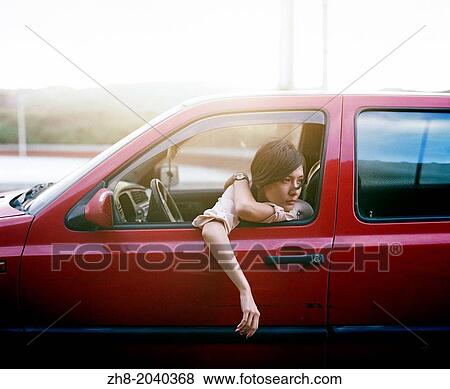 A young woman looks out of her window in a red car at sunset on the coast of Taiwan. View Large Photo Image Stock Photo - A young woman looks out of her window in a red car at sunset on the coast of Taiwan.. Fotosearch