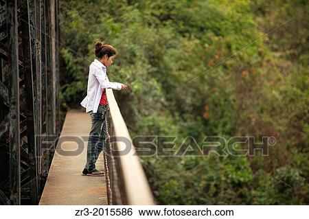 A young woman looks thoughtfully from a bridge near Battambang, Cambodia. View Large Photo Image Stock Photograph - A young woman looks thoughtfully from a bridge near Battambang, Cambodia.. Fotosearch