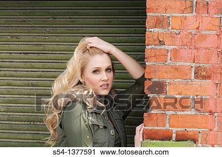 A young woman outdoors by a building View Large Photo Image Stock Image - A young woman outdoors by a building. Fotosearch