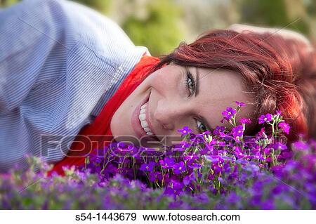 Stock Photo - A young woman outdoors in a flower garden. Fotosearch