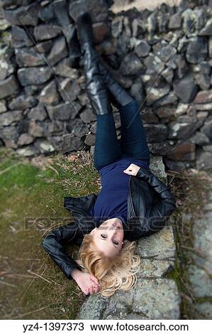 A young woman outdoors, laying on steps View Large Photo Image Stock Image - A young woman outdoors, laying on steps. Fotosearch