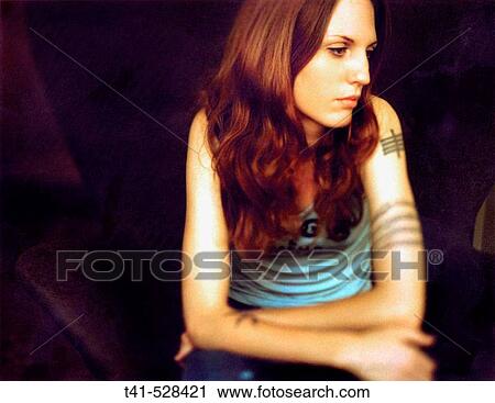 A young woman pauses meditatively. She wears a CBGB? s tank top and has many tattoos. View Large Photo Image Stock Image - A young woman pauses meditatively. She wears a CBGB? s tank top and has many tattoos.. Fotosearch
