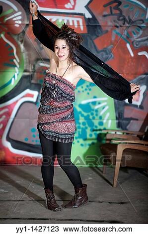 Stock Image - A young woman posing in front of a graffity.. Fotosearch