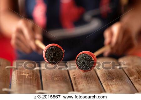 Stock Photo - A young woman practices playing a traditional Cambodian xylophone in Phnom Penh, Cambodia.. Fotosearch