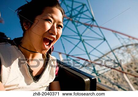 Stock Image - A young woman screams as she rides down a roller coaster in Southern California theme park.. Fotosearch