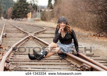 A young woman sitting on train tracks View Large Photo Image Picture - A young woman sitting on train tracks. Fotosearch