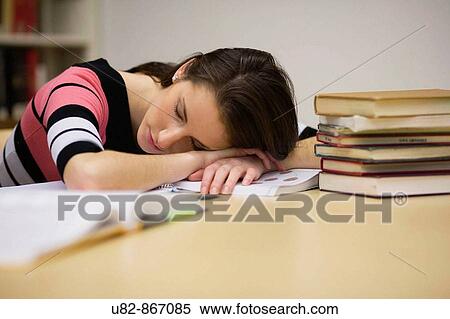 Stock Photography - A young woman sleeping in a library. Fotosearch