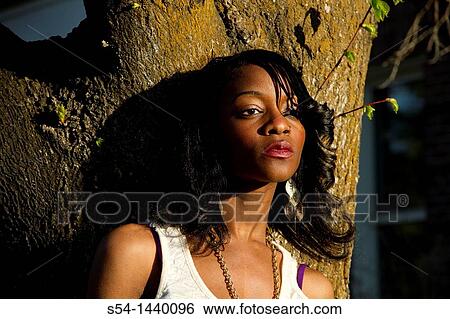 Stock Photograph - A young woman standing against a tree in Cheney, Washington, USA.. Fotosearch