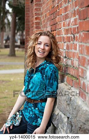 Stock Photography - A young woman standing by a brick building. Fotosearch