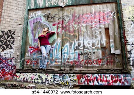 Stock Image - A young woman standing in an alley in Spokane, Washington, USA.. Fotosearch
