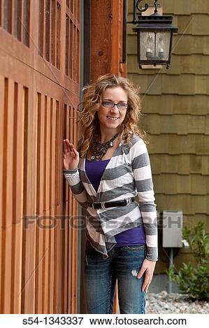 A young woman standing outdoors by a house View Large Photo Image Stock Photo - A young woman standing outdoors by a house. Fotosearch