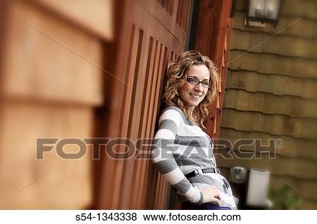 A young woman standing outdoors by a house View Large Photo Image Stock Photo - A young woman standing outdoors by a house. Fotosearch